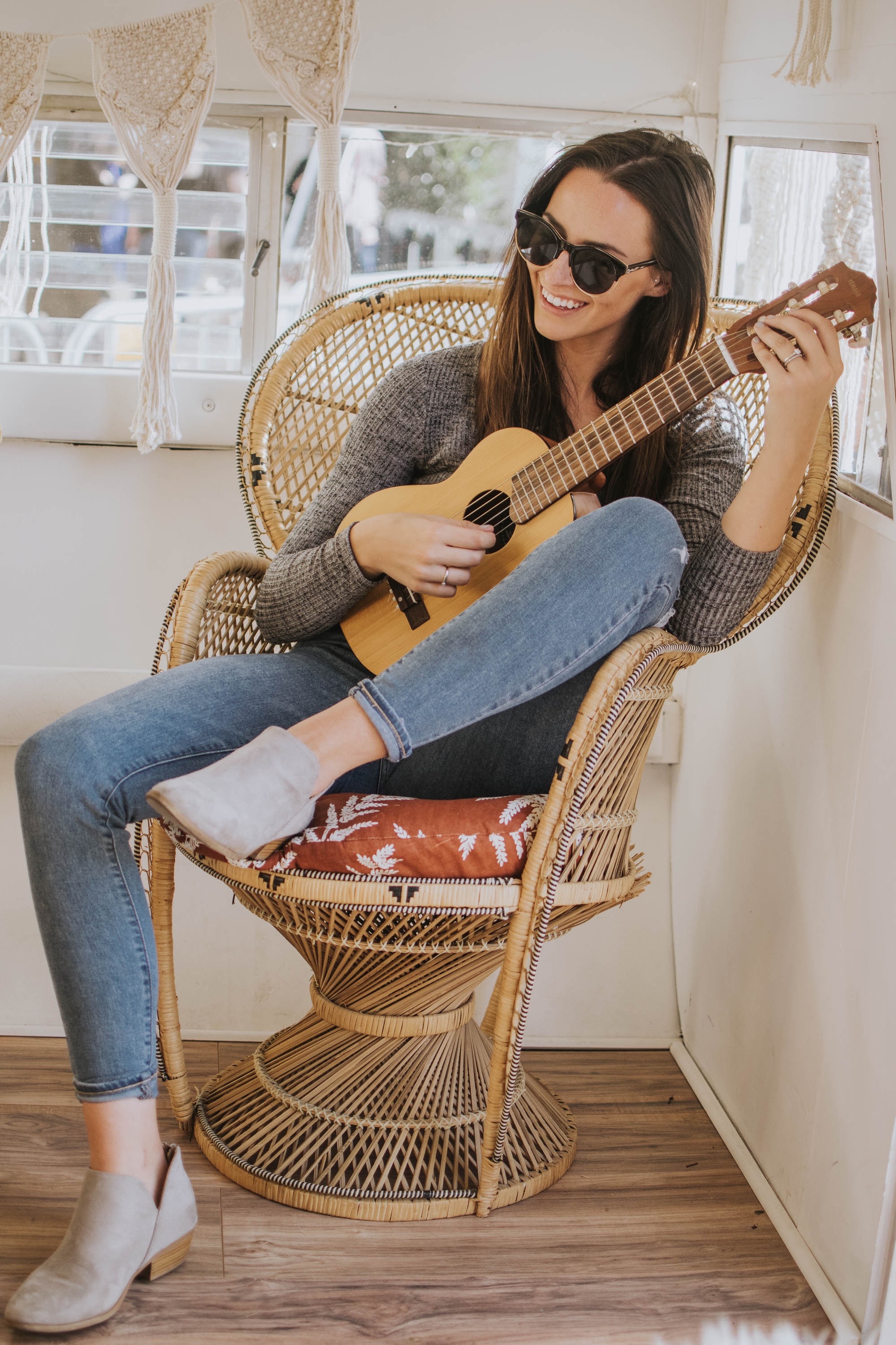 женщина на плетеном стуле с гитарой